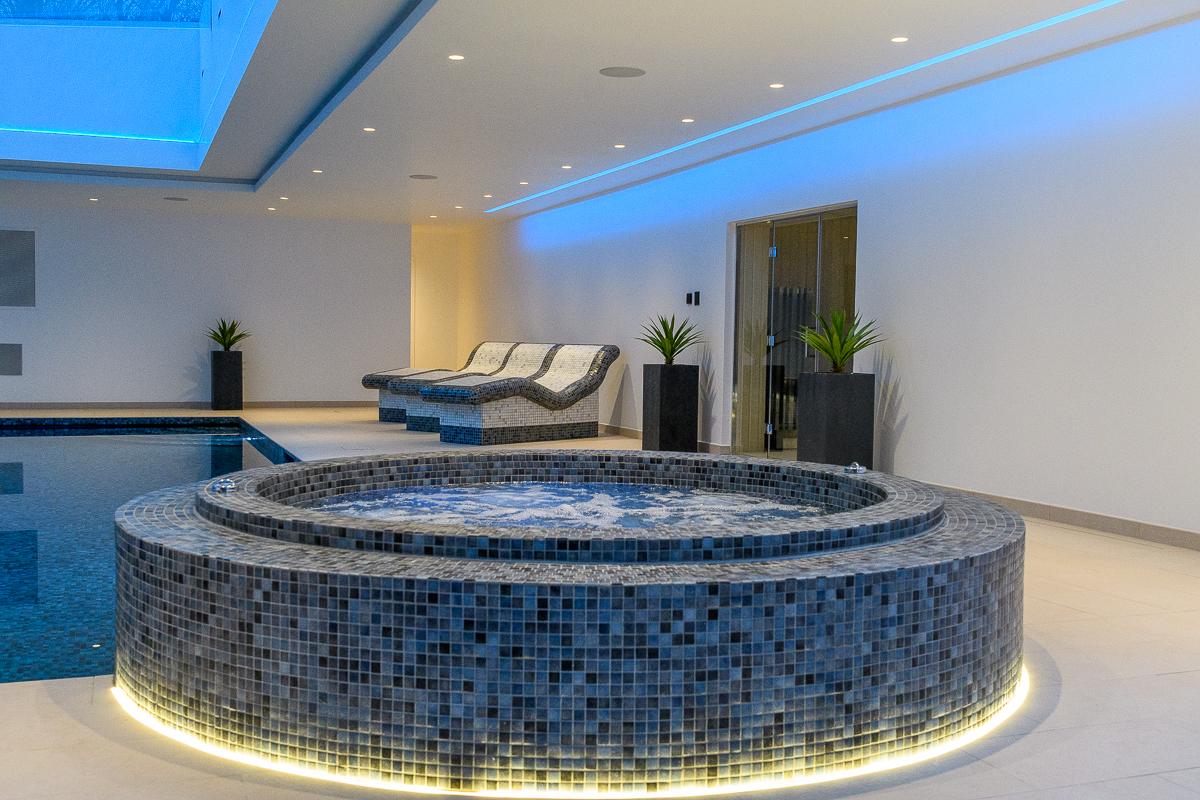 Completed leisure suite extension with a mosaic-tiled spa pool, loungers and concealed lighting
