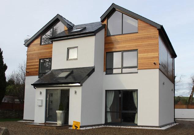 Completed contemporary new build house with render and cedar cladding, slate roof and dark framed windows