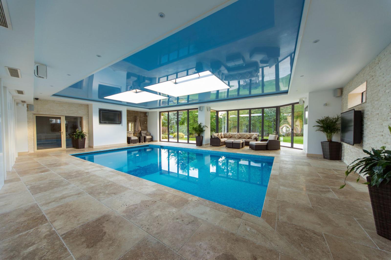 Swimming pool extension with travertine flooring, bi-fold doors to the garden and a gloss stretch ceiling