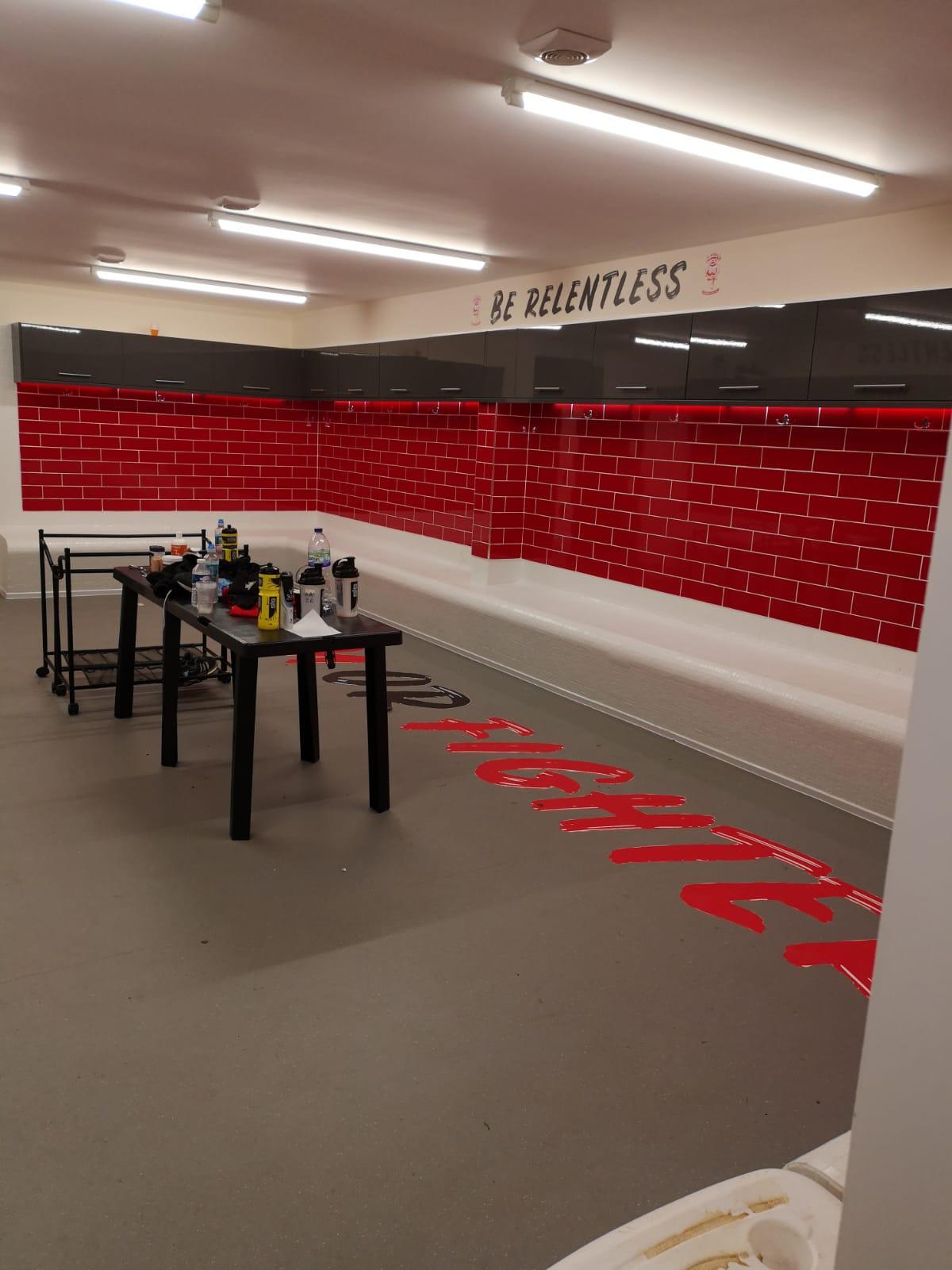 New build changing room fit-out with red metro tiling, black lockers and bench seating