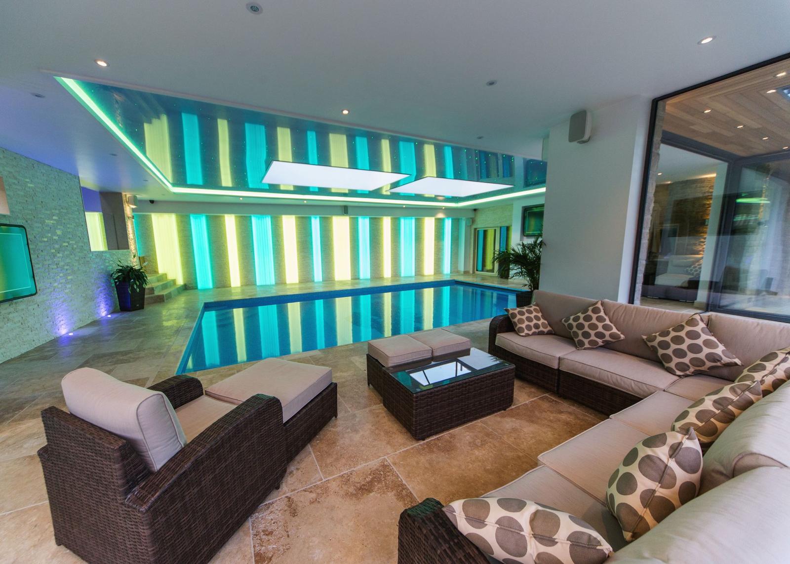 Indoor swimming pool and lounge extension with backlit feature wall and travertine flooring