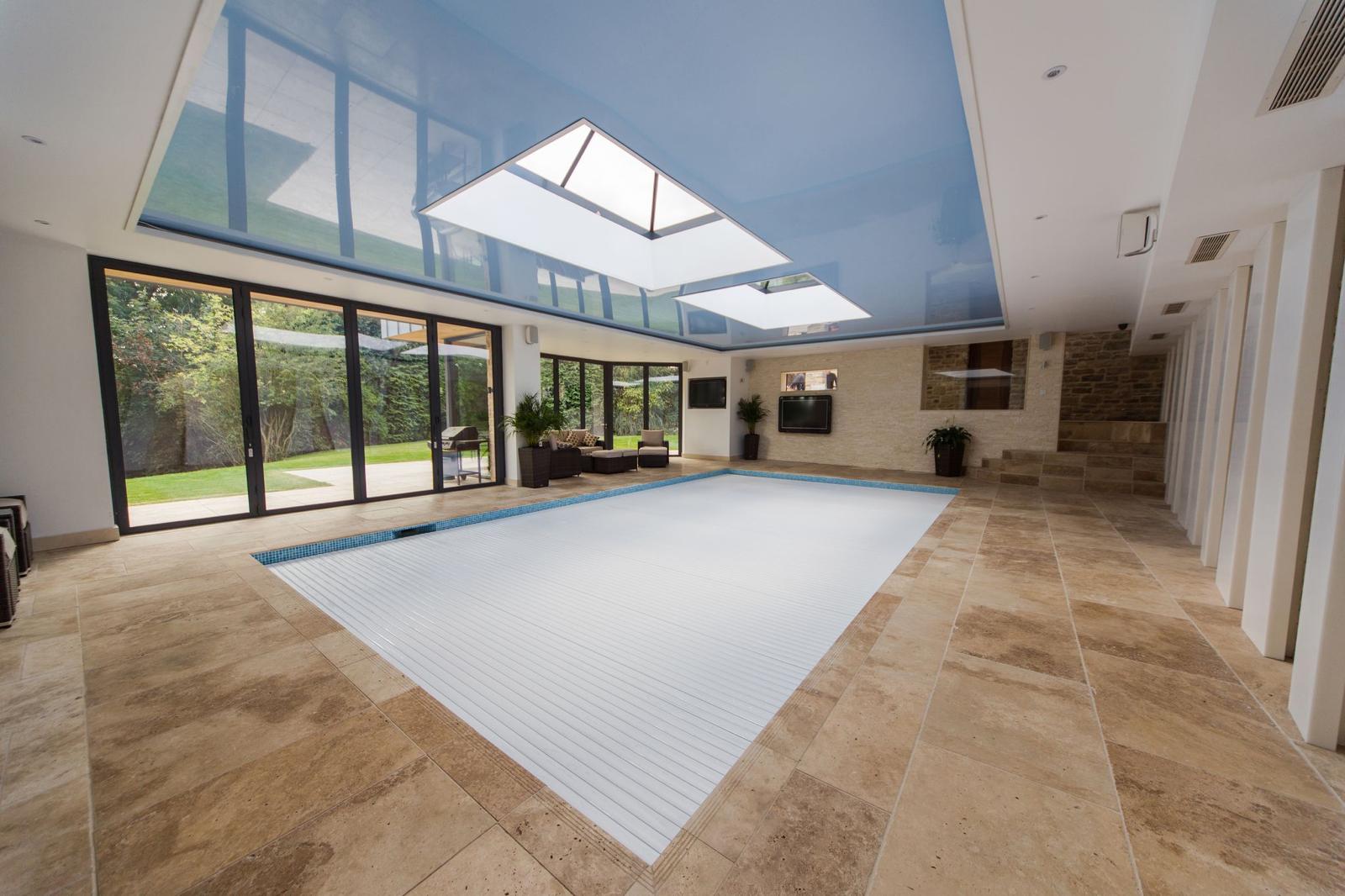 Completed indoor swimming pool extension with roof lanterns, travertine flooring and sliding doors to the garden