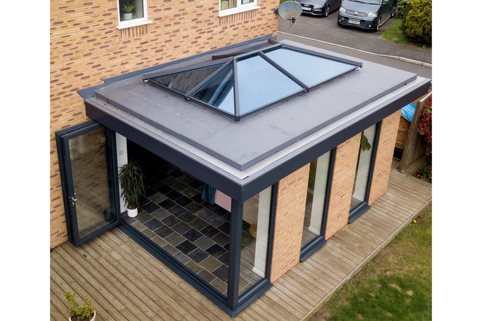 Rear extension with a grey flat roof, glazed roof lantern and anthracite bi-fold doors onto a timber deck
